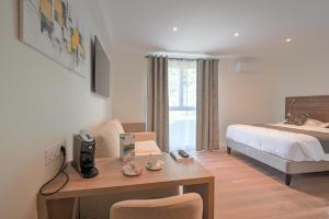 a hotel room with a bed and a desk with a computer at Logis Hotel Le Petit Casset in La Boisse +32 photos