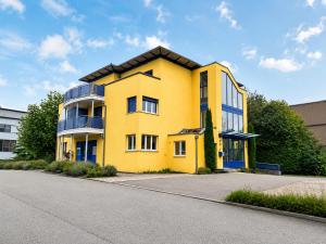 ein gelbes Gebäude am Straßenrand in der Unterkunft HelloStay Zug Studios in Hünenberg