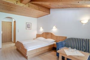 een slaapkamer met een bed, een bank en een tafel bij Hotel Kirchdach in Gschnitz +40 foto's