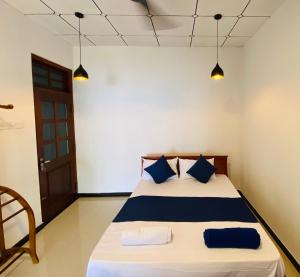 a bedroom with a bed with blue pillows at MAYU Homestay in Dickwella