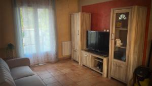 a living room with a tv and a entertainment center at Maison Grebert in Gouffern en Auge +3 photos
