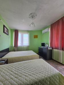 two beds in a room with green walls and red curtains at Студия Синя приказка in Sozopol +23 photos