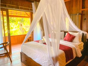 ein Schlafzimmer mit einem Bett mit Moskitonetz in der Unterkunft Desa Hostel in Munduk