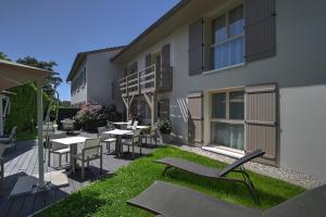 a patio with tables and chairs and a building at Logis Hotel Le Petit Casset in La Boisse