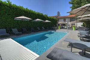 a swimming pool with chairs and umbrellas in a yard at Logis Hotel Le Petit Casset in La Boisse