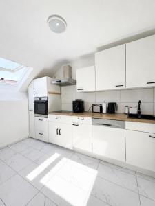 a white kitchen with white cabinets and appliances at Hostel am Rhein - Nierstein in Nierstein
