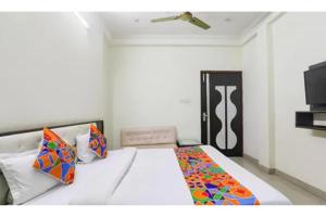 a bedroom with a large white bed with colorful pillows at FabHotel Sara Residency in Prayagraj
