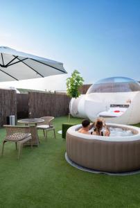 two people sitting in a hot tub in a yard with an airplane at Burbuja El Sueño del Duque in Villanueva de Tapia