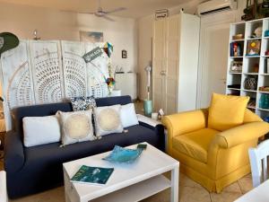 a living room with a blue couch and yellow chairs at Myrto Signature Suite - Aegina in Aegenitissa
