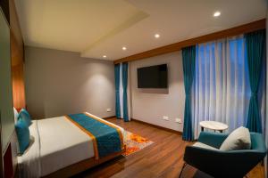 a bedroom with a bed and a chair and a television at Zone by The Park Darjeeling in Darjeeling