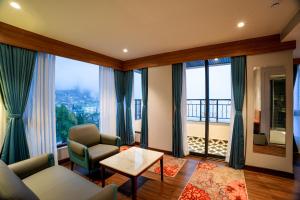 a living room with a couch and chairs and windows at Zone by The Park Darjeeling in Darjeeling