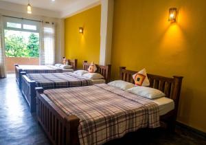 a group of four beds in a room with yellow walls at Queens Ark in Nallathanniya