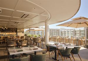 a restaurant with tables and chairs and umbrellas at Hilton Arcadia Los Angeles in Arcadia