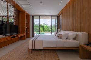 a bedroom with a large bed and a television at MUTHI MAYA Forest Pool Villa Resort - SHA Plus Certified in Mu Si
