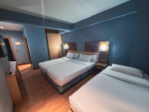 a hotel room with two beds and blue walls at Hotel Faranda Alisas Santander, Ascend Hotel Collection in Santander