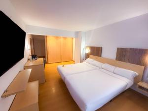 a bedroom with a large white bed and a television at Hotel Faranda Alisas Santander, Ascend Hotel Collection in Santander