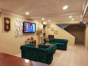 a living room with green couches and a flat screen tv at Shakim hotel in Cukai