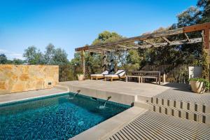 a swimming pool with a pergola and a picnic table at HeartStone Hill - Tiny House in Castlemaine