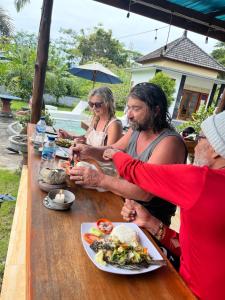 a group of people sitting at a table eating food at Batur Happy House in Kintamani
