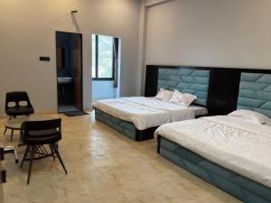 a bedroom with two beds and a table and a chair at Bhagwati Hotel And Rooms in Udaipur
