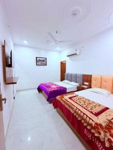 a bedroom with two beds and a flat screen tv at Nisha sadan in Vrindāvan