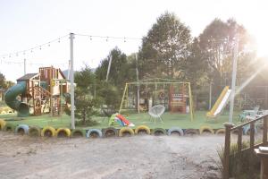 a park with a playground with a slide and swings at Pinitos Old Ranch & Cabañas in El Cristal