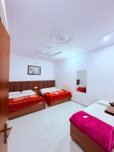 two beds in a large room with red sheets at Nisha sadan in Vrindāvan