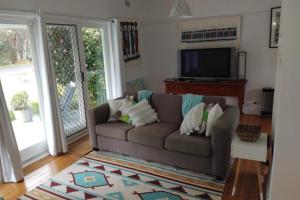 a living room with a couch and a tv at Sojourne - Walk to beach and Golf Club! in Shoalhaven Heads