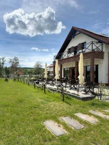 a building with tables and umbrellas in a field at Agroturystyka Myślinów - Black Horse Bar&Grill in Męcinka
