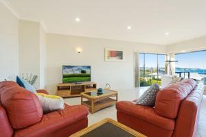a living room with two leather couches and a television at Kyeema in Tathra