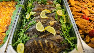 a tray of fish with lemon slices on top at Queen Nelly Park in Kiten