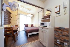 a small room with a kitchen and a table with a microwave at Omotenashi House Kawaguchi in Kawaguchi