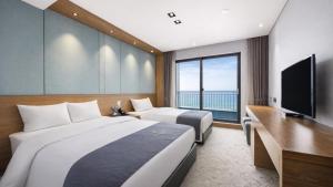 a hotel room with two beds and a flat screen tv at Incheon Grace Hotel in Incheon