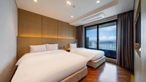 two beds in a hotel room with a large window at Incheon Grace Hotel in Incheon