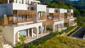 an external view of a building with grass roofs at Sereno Lombok Resort in Selong Belanak