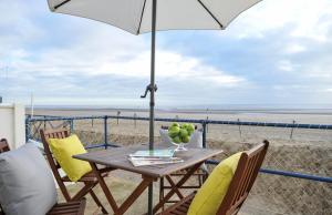 uma mesa e cadeiras com um guarda-sol na praia em Stowaway Beach House Camber Sands em Camber