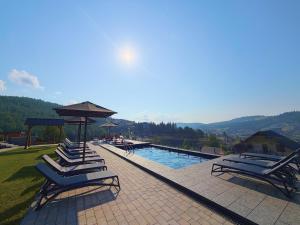a group of lounge chairs next to a swimming pool at Chalet Panorama (Апартаменти) in Bukovel