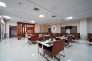 a dining room with tables and chairs and a television at Open Hotel by Olive - Ambicas Grand in Visakhapatnam