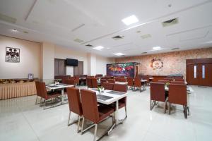 a dining room with tables and chairs and a screen at Open Hotel by Olive - Ambicas Grand in Visakhapatnam