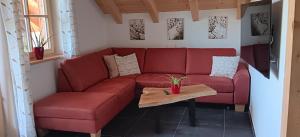 a red couch in a living room with a table at Bauernhofurlaub Eggcellence in Teisendorf