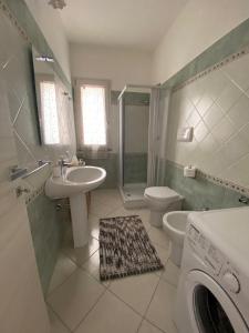 a bathroom with a sink toilet and a washing machine at Asfodelo in Galtellì