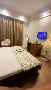 a bedroom with a bed and a desk and a television at Skycabinomaxe in Greater Noida