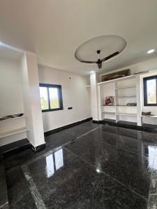 a living room with a ceiling fan and a room with white walls at Nishhh stay in Surūrnagar