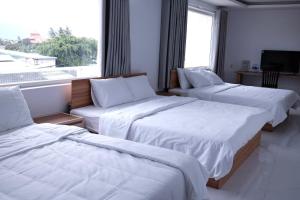 a hotel room with three beds and a window at Khách sạn Lumea in Cam Ranh