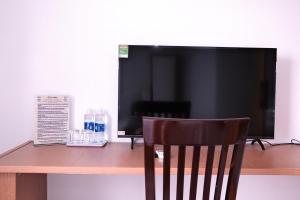 a wooden desk with a computer monitor and a chair at Khách sạn Lumea in Cam Ranh