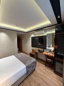 a bedroom with a bed and a desk and a television at Nil Hotel in Gaziantep