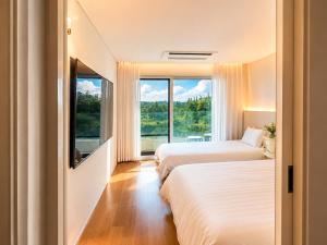 two beds in a room with a large window at Jeju BunkerHotel&Resort in Seogwipo