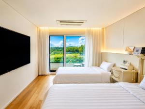 a hotel room with two beds and a large window at Jeju BunkerHotel&Resort in Seogwipo