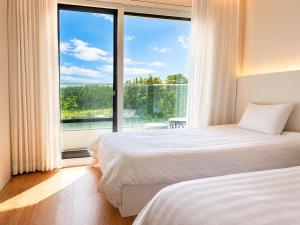 a bedroom with two beds and a large window at Jeju BunkerHotel&Resort in Seogwipo