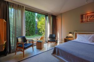 a bedroom with a bed and two chairs and a large window at Warehouse By The Stay in Alaçatı +51 photos